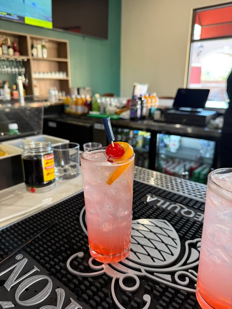 A signature cocktail with a golf-ball garnish on the bar